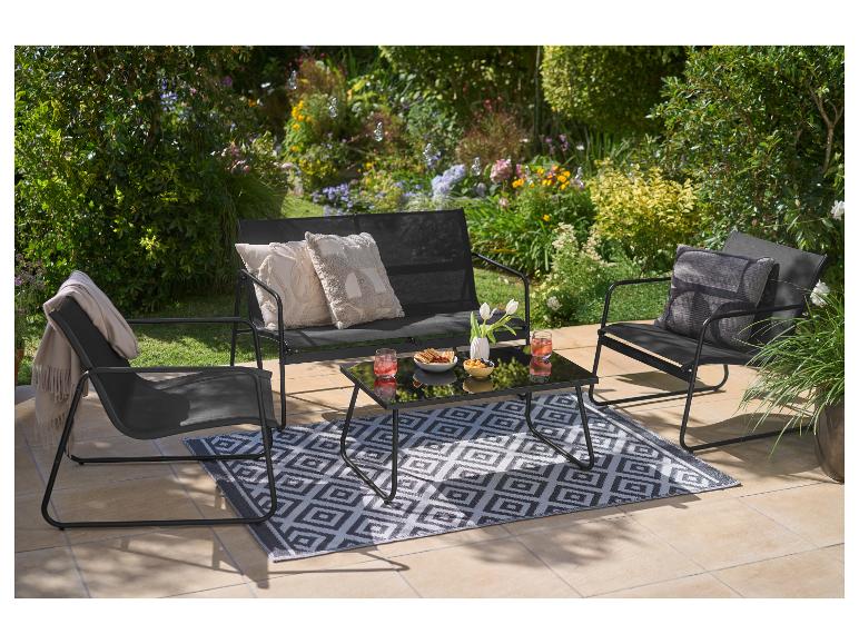 Ensemble de mobilier de jardin avec chaises noires, banc, table basse et tapis sur une terrasse.