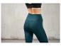 Une femme porte un legging vert foncé.