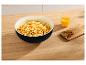 Popcorn dans un bol noir avec boisson à l'orange et noix sur une table en bois.