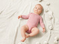 Un bébé sur une couverture tricotée avec des pompons.