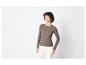 Une femme porte un pull en maille marron avec un pantalon blanc.