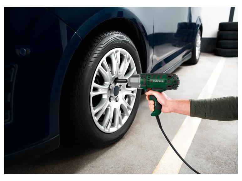 Une personne utilise une clé à chocs Parkside pour changer une roue de voiture.