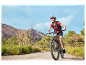 Une femme souriante fait du vélo électrique Orbea sur un sentier de montagne.