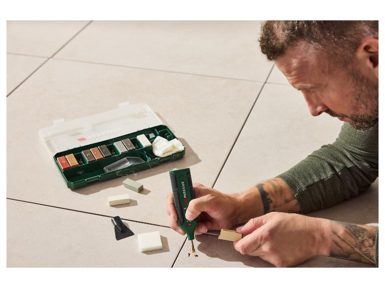 Un homme utilise un kit de réparation PARKIDE pour combler un trou dans un sol clair.