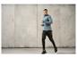 Un homme en chemise grise et pantalon noir avec des baskets, qui court.