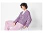 Modèle avec un cardigan en tricot violet et un pantalon en tissu rose.