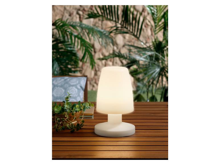 Une lampe blanche avec une base ronde sur une table en bois.