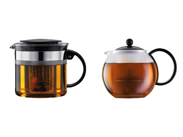 Deux théières en verre avec poignées et couvercles noirs, remplies de thé infusé.