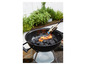 Un barbecue noir avec du charbon de bois qui est allumé avec un briquet à gaz.