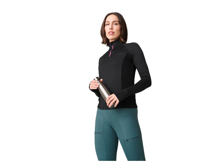 Femme en veste de sport noire et leggings bleus tenant une bouteille d'eau.