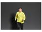 Un homme portant une veste jaune et un pantalon de survêtement noir.