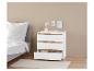Une commode blanche avec trois tiroirs dans une chambre à coucher.