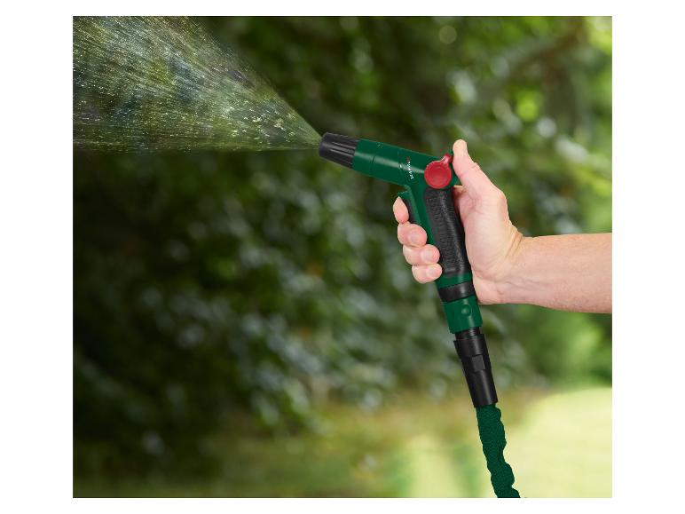 Main tenant une lance d'arrosage verte pulvérisant de l'eau, avec un arrière-plan vert flou.