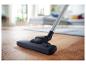 Aspirateur nettoyant la saleté d'un parquet en bois dans un salon lumineux.