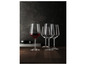 Trois verres, dont un avec du vin rouge, sur une table en bois.