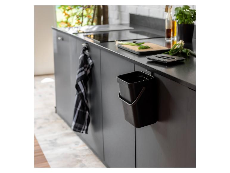 Une poubelle noire accrochée à une armoire de cuisine.