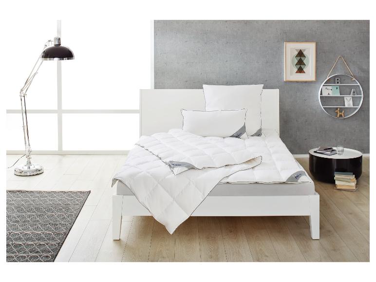 Lit blanc avec couette et oreillers, lampadaire, tapis et table d'appoint dans une chambre moderne.