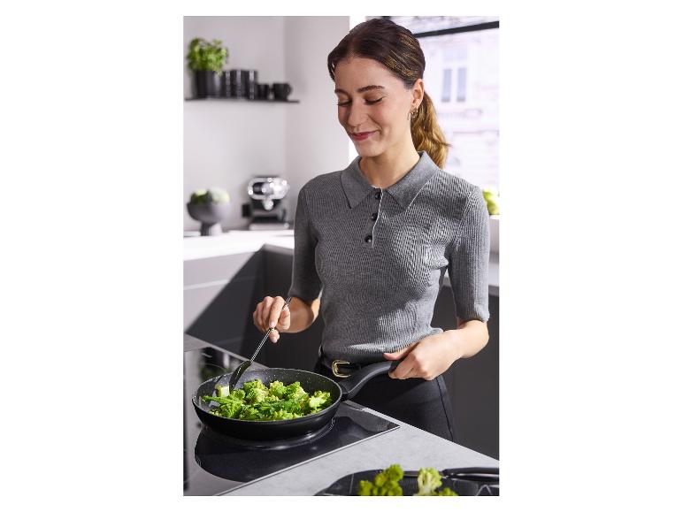 Femme cuisinant du brocoli dans une poêle sur une plaque à induction dans la cuisine.