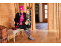 Femme en bonnet rose, veste noire et tenue de ski enfilant des gants.