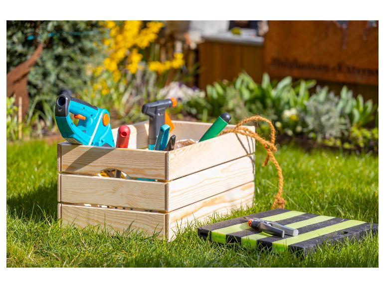 Outils de jardinage dans une caisse en bois sur la pelouse.