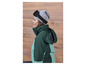 Une femme porte une veste de ski verte avec un bonnet gris et des lunettes de ski 'Crivit'.