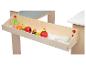 Un tiroir en bois avec des jouets de jeu de rôle: fruits et craies.