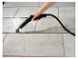 Main tenant un nettoyeur vapeur, nettoyant des carreaux de sol gris clair à la vapeur