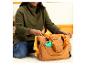 Femme souriante en pull vert plaçant un jouet Winnie l'Ourson dans un sac à langer marron.