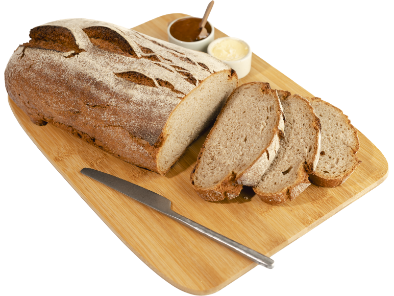 Pain de campagne tranché avec beurre et confiture sur une planche en bois.