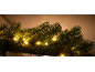 Gros plan d'une guirlande verte festive avec des lumières LED blanc chaud sur fond beige.