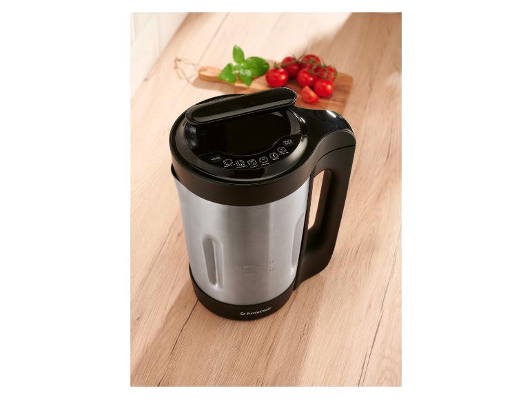 Machine à soupe et smoothie sur une table en bois, avec tomates et basilic.