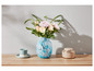 Un vase de fleurs, une tasse à thé et une boîte sur une table en bois.
