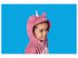 Fille en pyjama licorne rose, souriant sur fond bleu.