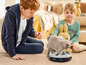 Un chat joue avec un jouet interactif pour chat, près d'un garçon et d'une fille.