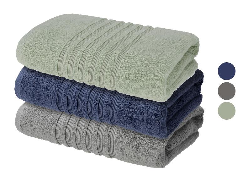 Pile de trois serviettes pliées de couleurs vert clair, bleu foncé et gris.