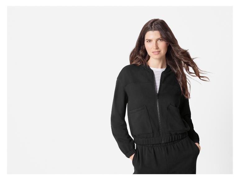 Une femme portant un pantalon de survêtement noir et une veste bomber noire.
