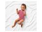 Bébé portant un body rose sur une couverture blanche.