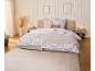 Chambre élégante avec parure de lit fleurie, jeté de lit en tricot et tapis assorti