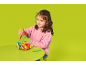 Fille jouant avec un jeu de construction magnétique coloré sur une table verte.