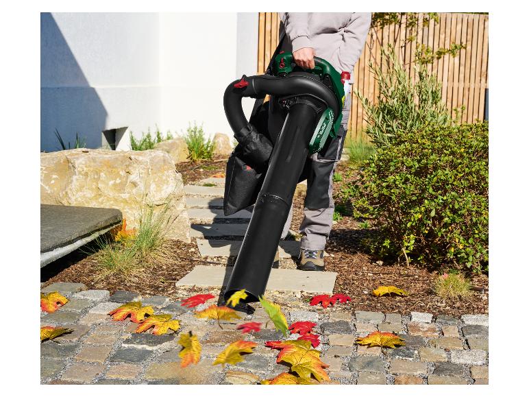 Une personne utilise un souffleur de feuilles pour nettoyer les feuilles d'automne d'une allée pavée.