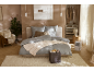 Chambre confortable avec linge de lit gris, tapis clair, fauteuil et dressing ouvert.