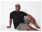 Un homme portant un t-shirt noir et un short vert olive.