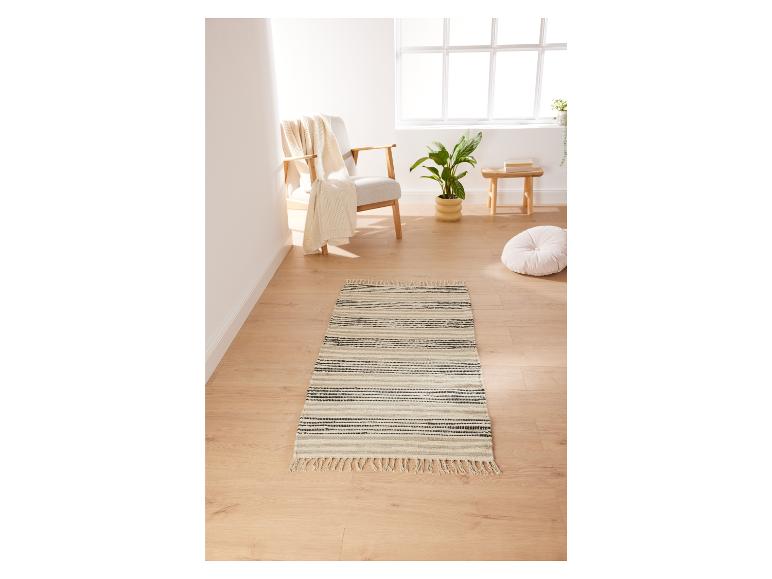 Un tapis rayé avec des franges dans un salon lumineux.