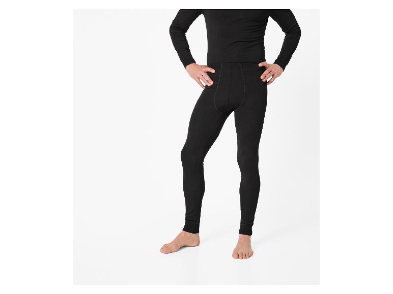 Homme en collant noir et haut à manches longues, les mains sur les hanches.