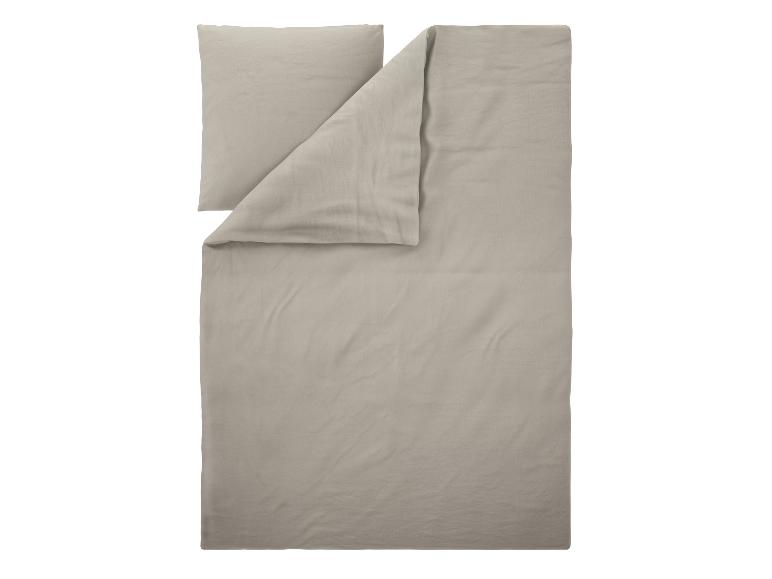 Parure de lit beige clair avec housse de couette et taie d'oreiller pliées.