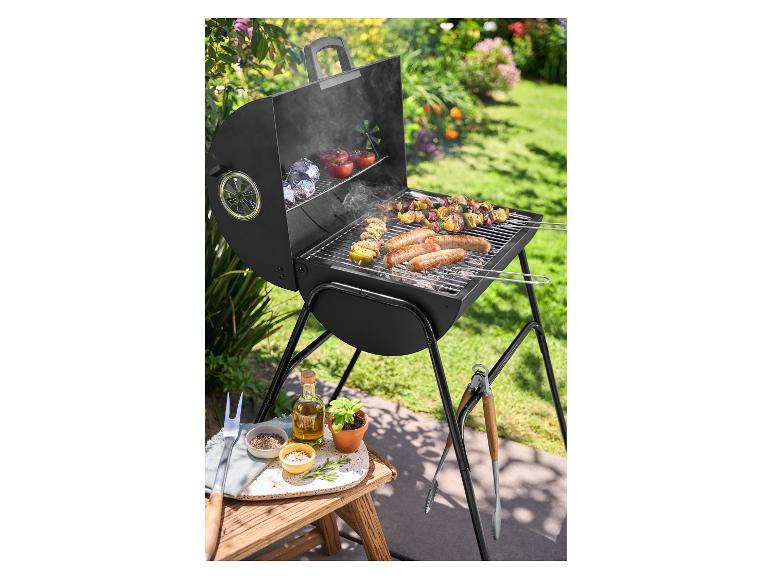 Barbecue à charbon de bois avec saucisses et brochettes dans un jardin ensoleillé.