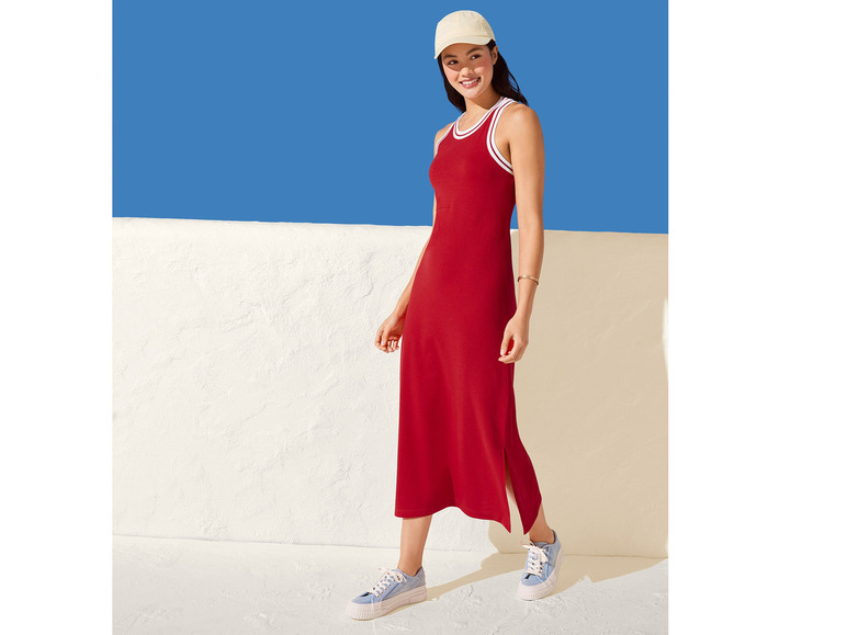 Une femme portant une robe rouge avec des rayures blanches et des baskets bleues.