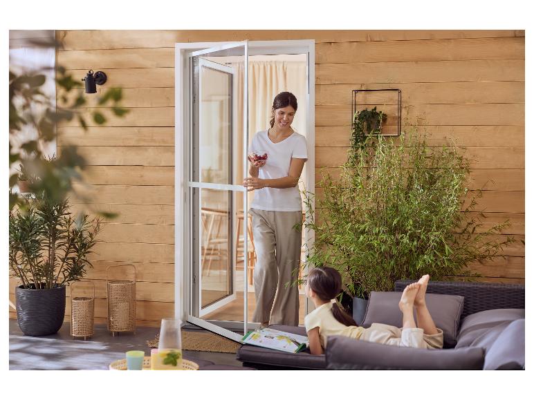 Femme avec des baies ouvrant une porte-fenêtre à une fille se relaxant sur des meubles d'extérieur.
