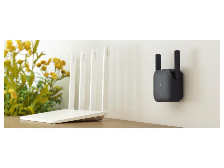 Routeur MiWiFi blanc et amplificateur de signal Xiaomi noir au mur.