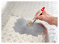 Une main appliquant de la peinture grise sur une surface métallique avec un pinceau Parkside.